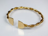 Lot 251 - A yellow metal torque bangle, of twist design,...