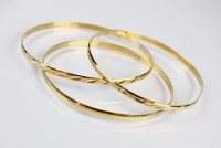 Lot 256 - Three yellow metal bangles, each stamped '750',...