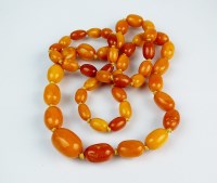 Lot 266 - A graduated amber bead necklace, comprising...