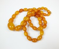 Lot 63 - A graduated amber bead necklace, comprising...