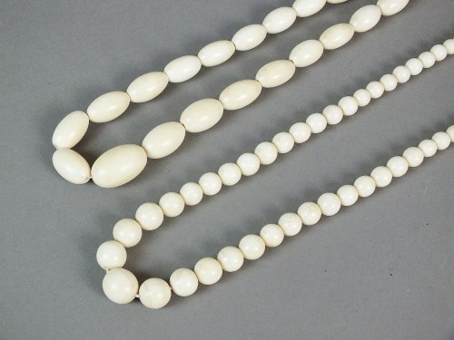 Lot 385 - An ivory graduated oval bead necklace, 1920s,...
