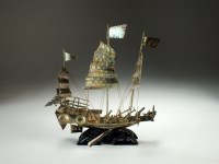 Lot 196 - A white metal model of a junk, raised on stand,...