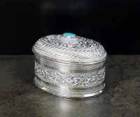 Lot 38 - A white metal oval box and cover, with chased...