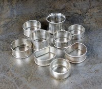 Lot 101 - A collection of nine silver napkin rings,...