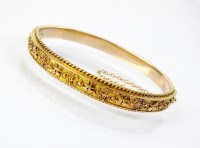 Lot 180 - A late 19th century yellow metal hinged bangle,...