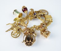 Lot 214 - A yellow metal charm bracelet with attached...