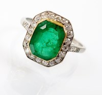 Lot 245 - An emerald and diamond oblong cluster ring,...