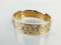 Lot 83 - A 9ct gold hinged bangle, with bright cut...