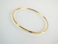 Lot 110 - A yellow metal bangle, with ribbed decoration,...