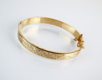 Lot 122 - A 9ct gold hinged bangle with bright cut...