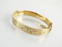 Lot 133 - A 9ct gold hinged bangle, with bright cut...