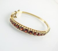 Lot 141 - A 9ct gold graduated garnet hinged bangle,...