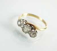 Lot 180 - A graduated three stone diamond crossover ring,...