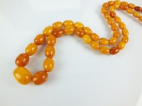 Lot 84 - A graduated amber bead necklace, comprising...