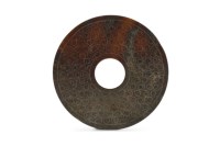 Lot 47 - A Chinese dark russet jade disc, Bi Warring...